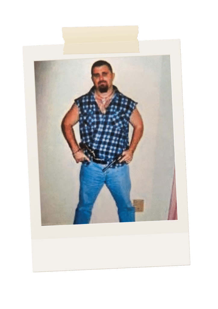 Polaroid-style photo of 'Donny' in a sleeveless flannel shirt posing with guns, reflecting the gritty criminal environments explored in Donny’s Deathwish.